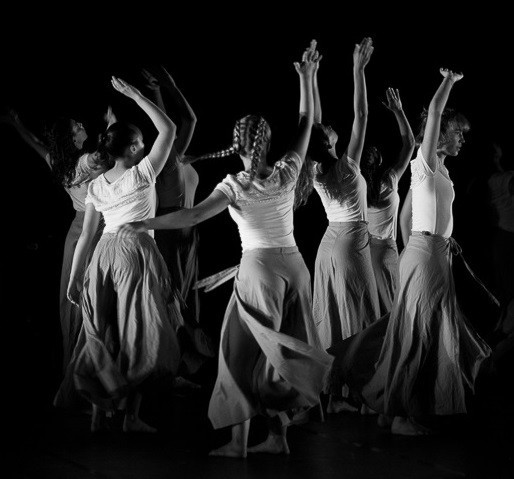 Un groupe de danseuses contemporaines sur scène, levant les bras pendant leur chorégraphie
