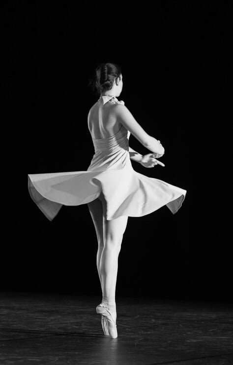 Une danseuse classique sur scène, en tutu et sur pointes